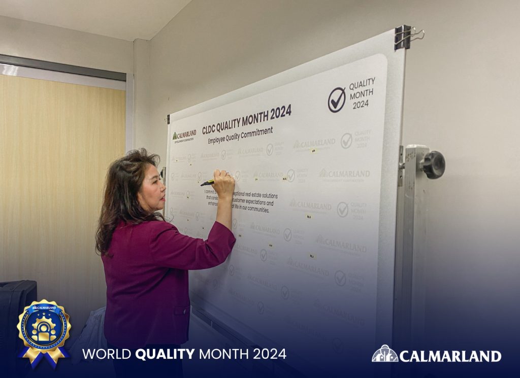 Calmarland President Mary Bel Calayan signing the Employee Quality Commitment board during World Quality Month 2024, showcasing Quality in Property Development.