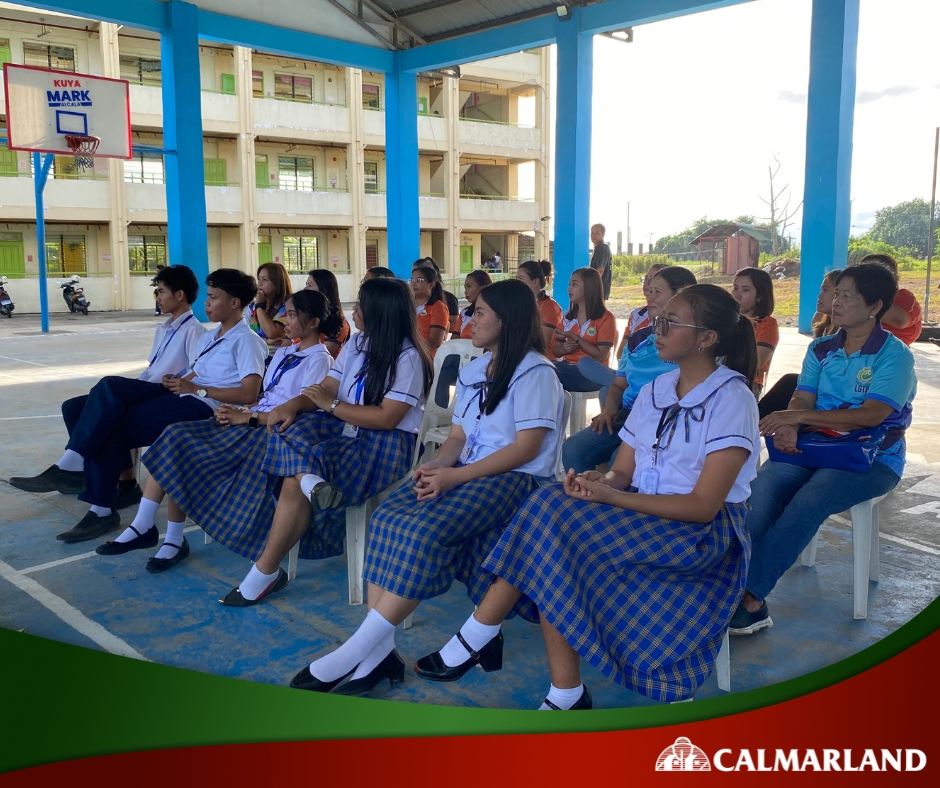 A group of students in uniform sit attentively at a ceremony for Calmar Land's donation of a waiting shed to their school, showcasing the real estate company's community support.